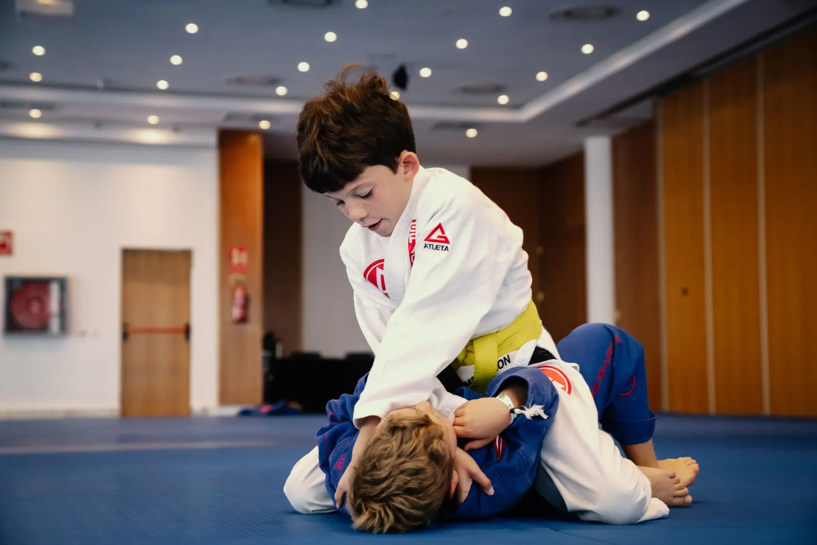 A young student in a white gi practising top control