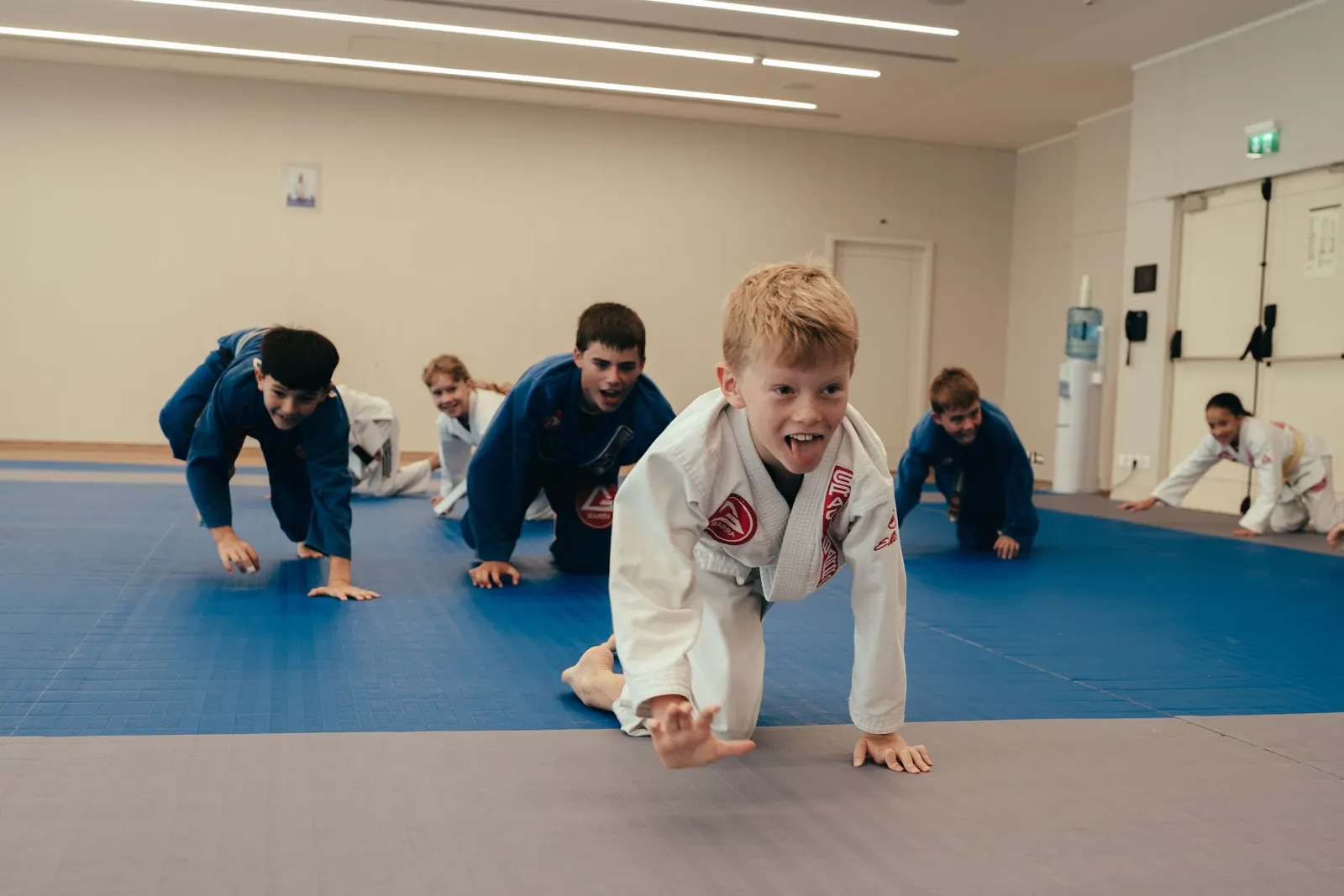 Young students crawling across the mats during a warm-up